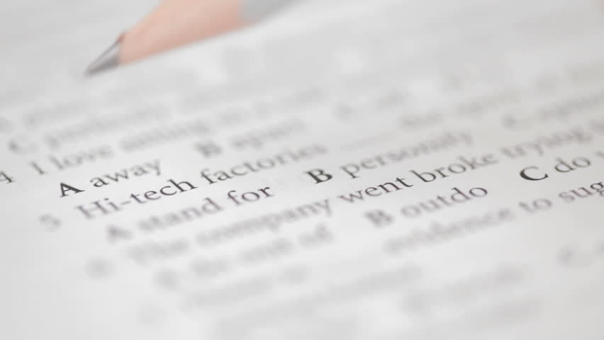 Student filling out answers to a book of English grammar with a pencil