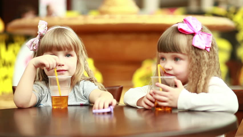 Two girls drinking juice and looking at camera