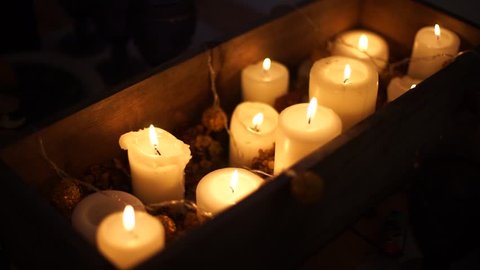 Lots of candles lit at Christmas, placed in a wooden box.