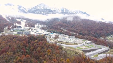 Aerial View. Flying over the city in the mountains. Bobsled track in Sochi.  Sochi Krasnaya Polyana Aibga. Aerial drone shot. 4K 30fps 