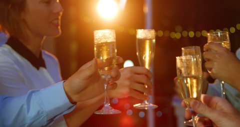 Close-up of Caucasian businesspeople group toasting glasses of champagne in office at night