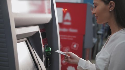 young woman inserting a credit card to ATM, beautiful girl banking