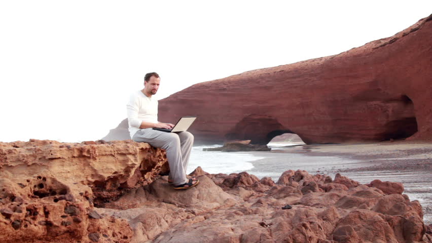 Man with laptop chatting on the rocks, Legzira beach
