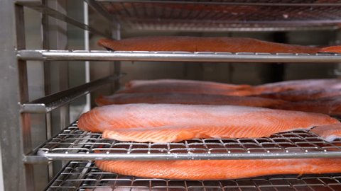 Many pieces of salmon fillet on the shelves ready for smoking.