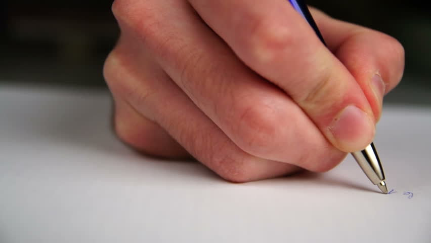 Hand writing a letter on a piece of paper.