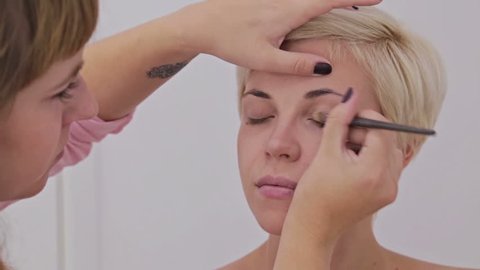 Professional make-up artist applying cream base eyeshadow primer to model eye. Beauty, makeup and fashion concept