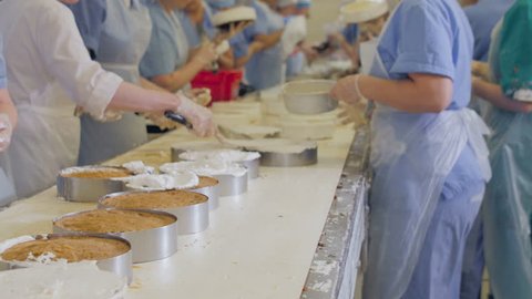Cakes production factory. Hands cooking, preparing cakes on a conveyor. Decorating cakes at a bakery.