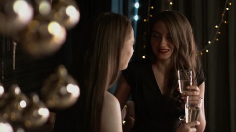 Beautiful girls with glasses of champagne emotionally speak in a Christmas interior