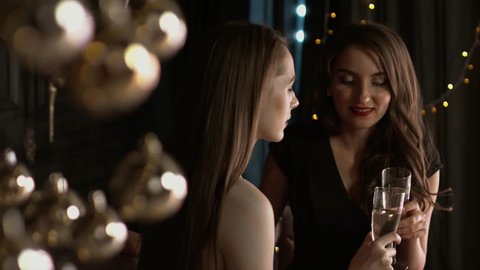 Beautiful girls clink glasses and drink champagne in a Christmas interior