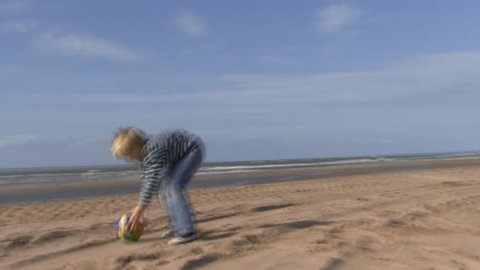 WIDE SHOT, Handheld, Father and son playing football on beach