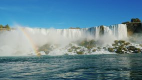 Slow motion video: A stunning Niagara Falls and a Rainbow. Bottom view. falling water weight raises a lot of spray and mist