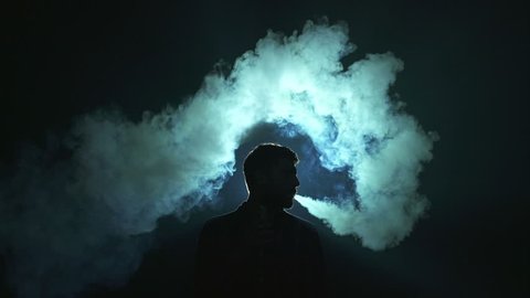 The man smoke electric cigarette on the dark background
