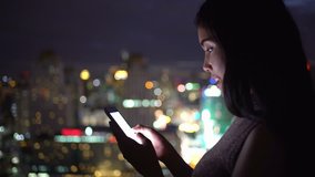 Woman use smartphone  very happy for communicate including connection her friend ,watching funny video,email, chat and shopping online in city at night : Gimbal  shot