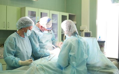 Surgeon and surgical team are performing cosmetic surgery on breasts in hospital operating room. Breast augmentation. Mammoplasty. Breast enlargement. Liposuction. Emergency care. Surgery detail.