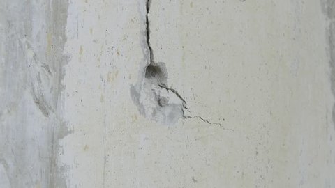 Ungraded: Drill hole / drill machine / concrete wall. Drill breaks through the concrete wall, showering plaster. Source: ungraded H.264 from camera without re-encoding. (av33013u)