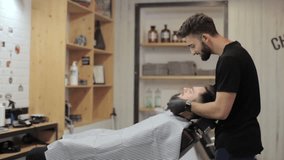 Funny video about barber combing beard of client and dancing at a barber shop.