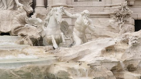 close up of a horse and triton statue at trevi fountain in rome, italy