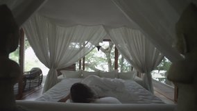 Sleeping girl wakes up. Romantic bed under the canopy. Bedroom in the forest. Woman stretches, yawning and waking up in bed. Wakes up and quickly gets out of bed. Overslept! Slow Motion