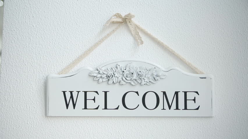 welcome word in vintage letterpress wood type on a grunge painted barn wood background