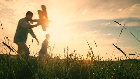 Father and Son are Playing and Running with Model Airplane in the Field. Golden Hour.