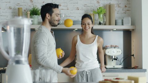 Slow Motion of a Guy Impressing His Lady with Juggling Oranges on the Kitchen. Shot on RED Cinema Camera in 4K (UHD).