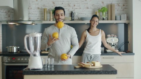 On the Kitchen Beautiful Couple Makes Breakfasts. Guy Impresses His Lady By Juggling with Oranges. Shot on RED Cinema Camera in 4K (UHD).