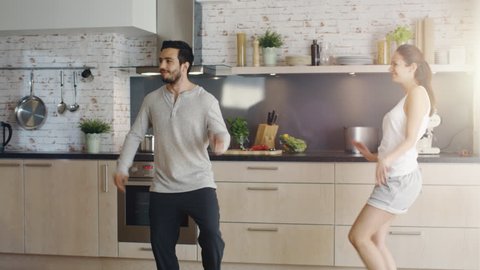 Happy Couple Creatively Dances in the Kitchen. Both are Adorable and Smiling. Shot on RED Cinema Camera in 4K (UHD).