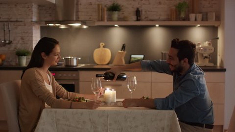Young Couple Having Candlelight Dinner. Talking. Man Pours Wine in Glasses. Shot on RED Cinema Camera in 4K (UHD).
