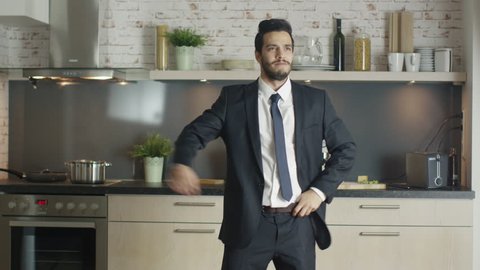 Classy and Handsome Young Businessman Dances Energetically at His Kitchen. Shot on RED Cinema Camera in 4K (UHD).