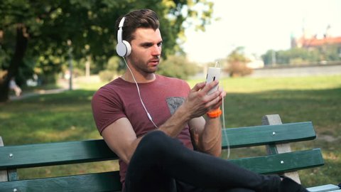 Handsome man doing selfies on smartphone while listening music in park
