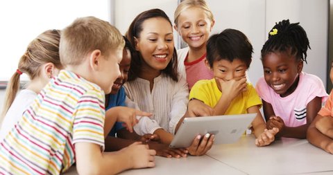 Front view of Caucasian female teacher teaching school kids on digital tablet in classroom at school స్టాక్ వీడియో