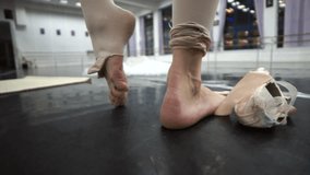 Professional ballerina warms up feets without pointe shoes, sits on the floor and warms feets by hands. Wide angle.After Hard training in ballet class.Full HD stock video clip 1920 X 1080