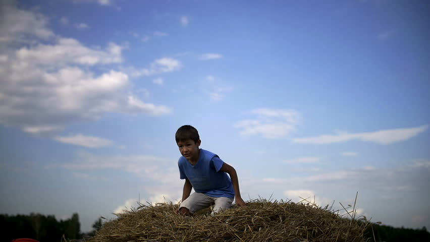 boy jumping on haystack, enjoys having fun win, slow motion