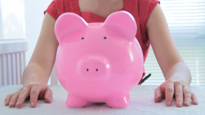 Female checking savings in piggy bank and looking disappointed