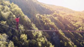 Drone Footage Of Man Balancing On Tightrope Above Mountains Walking Extreme Sport Danger Leisure Adventure Brave Slacklining Fear Sunny