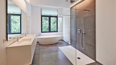 Bathtub in corian, Faucet and shower in tiled bathroom with windows towards garden