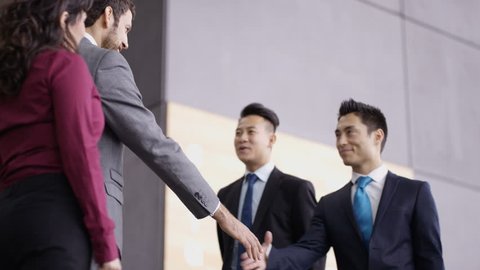 4K Business teams greet each other and shake hands in modern office building (UK-Oct 2016)
