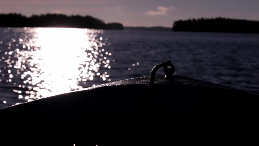 Backlight shot of the bow of a motorboat heading towards sun at a lake.