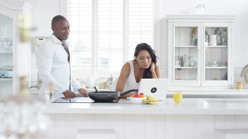 4K Couple dancing in the kitchen at home, listening to music on laptop (UK-Oct 2016)