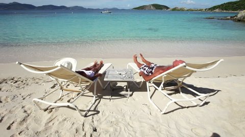 elderly couple relaxing in beach chairs on dead man's bay, peter island