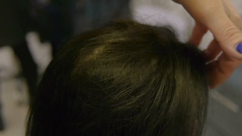 Hair stylist stroking her hands long hair woman in a beauty salon