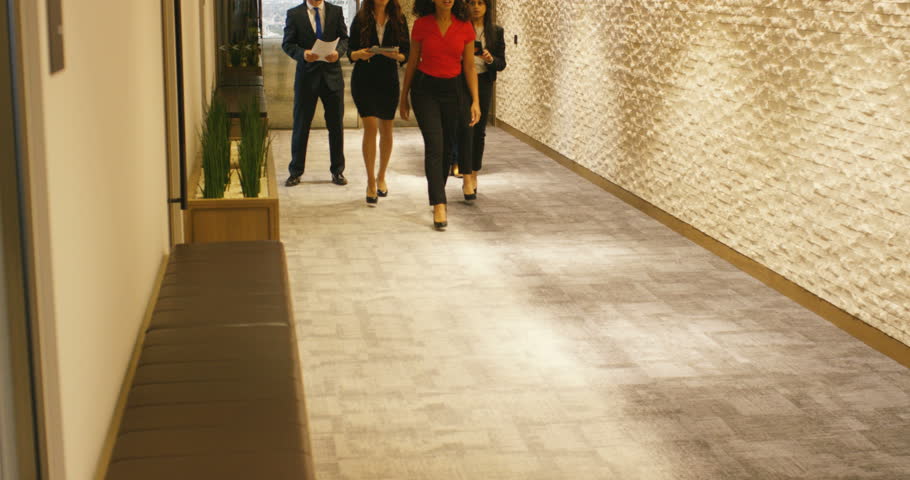 4K Bossy female business executive giving instructions to team of assistants in large corporate building