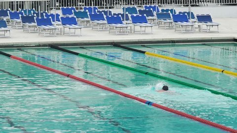 Lone man doing front crawl in sports club swimming pool, healthy lifestyle