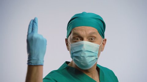 Funny man wearing scrubs and face mask pretending to be proctologist, crazy joke