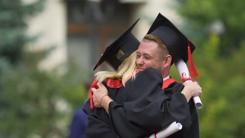 Best friends hugging warmly and laughing, celebrating graduation from university