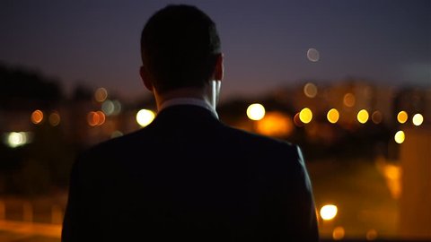 A man on top of a building at night looking to city