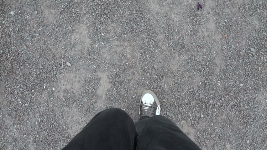 Point of view of feets walking on gravel.