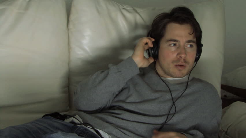 MEDIUM SHOT PAN OF A MAN LISTENING TO MUSIC