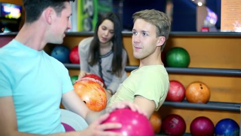 Three students two boys with one girl talk at bowling club, then smile and show thumbs up
