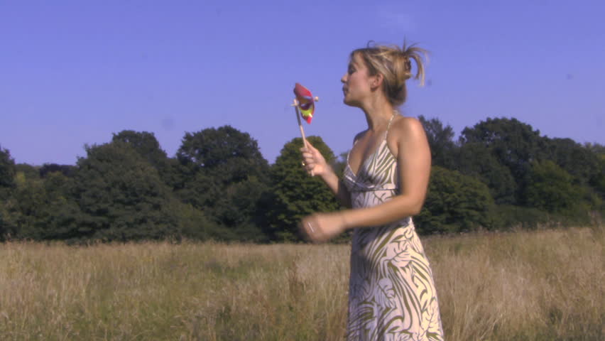 MEDIUM SHOT OF A WOMAN BLOWING A PINWHEEL